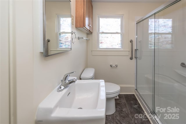 bathroom with a stall shower, baseboards, a sink, and toilet
