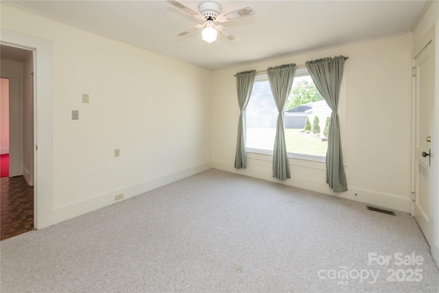 empty room featuring carpet floors, a ceiling fan, visible vents, and baseboards
