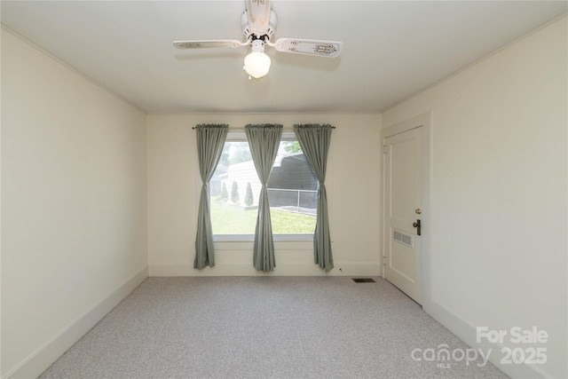 carpeted empty room with visible vents, a ceiling fan, and baseboards
