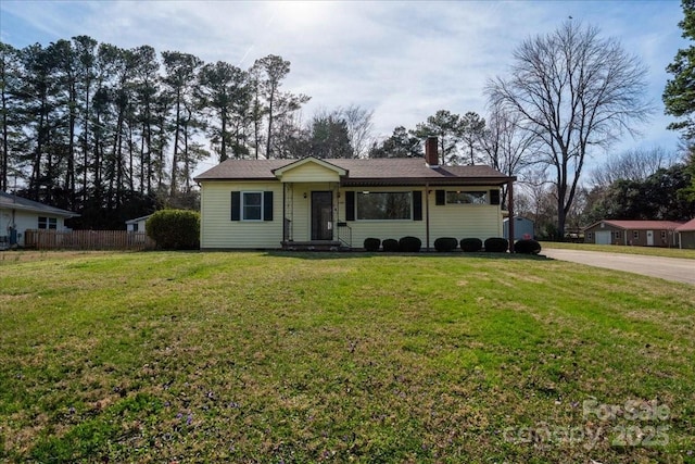 view of front of house with a chimney, concrete driveway, a front lawn, and fence