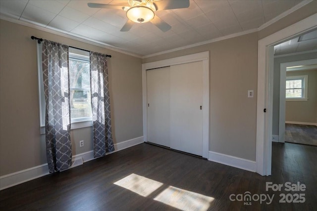 unfurnished bedroom featuring wood finished floors, multiple windows, and ornamental molding