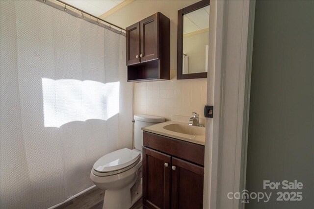 full bathroom with vanity, wood finished floors, tile walls, toilet, and backsplash