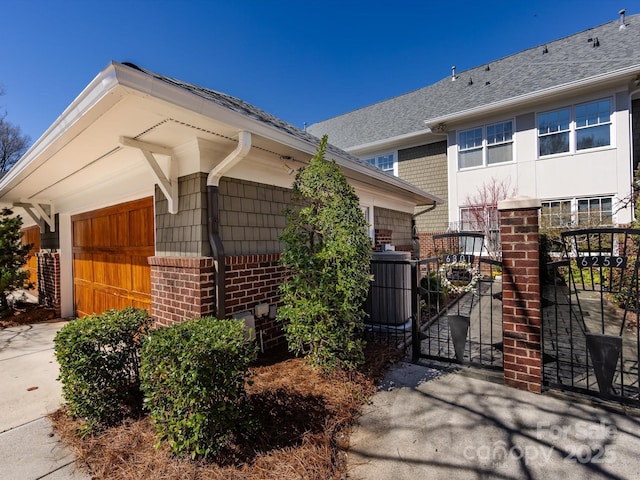 6301 Park Dr S, Charlotte, NC 28210 - view of side of property with brick siding, a garage, a gate, roof with shingles, and central AC