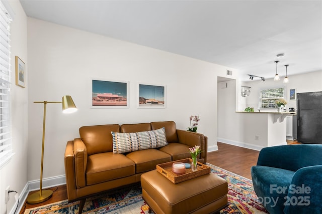 living room with visible vents, baseboards, and wood finished floors