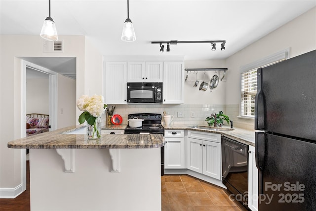 kitchen featuring visible vents, a sink, black appliances, white cabinets, and tasteful backsplash