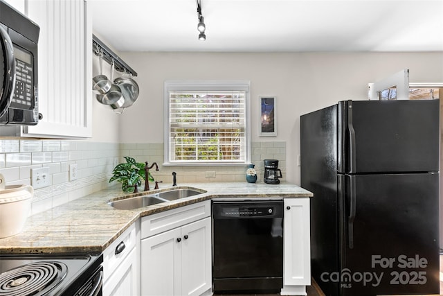 kitchen with tasteful backsplash, light stone counters, white cabinets, black appliances, and a sink