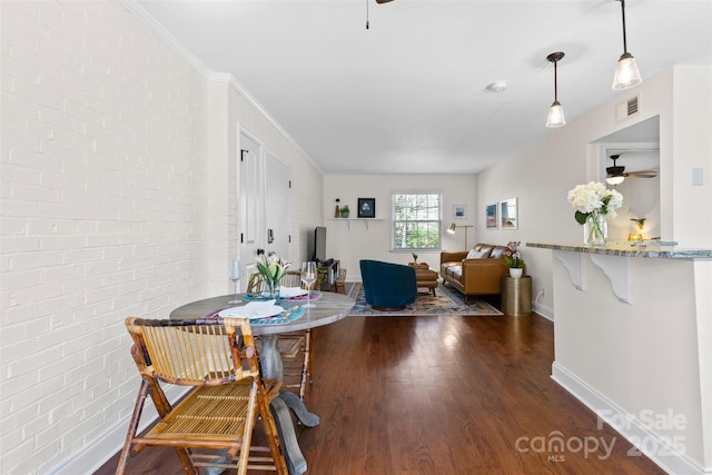 dining space with visible vents, brick wall, baseboards, a ceiling fan, and dark wood-style flooring