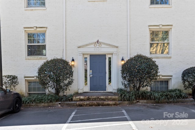 doorway to property featuring uncovered parking and brick siding