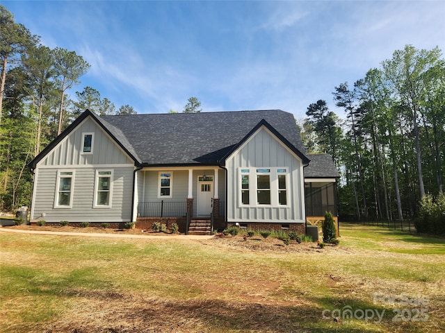 view of front of home featuring a shingled roof, covered porch, board and batten siding, and a front lawn