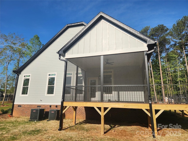 back of house with board and batten siding, crawl space, a ceiling fan, a sunroom, and central AC