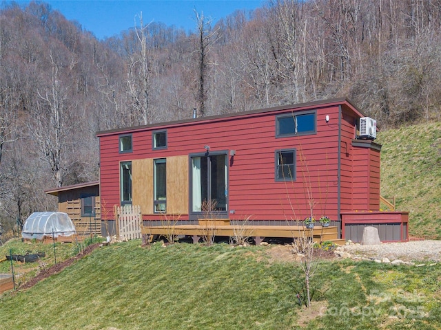 rear view of property featuring a view of trees and a lawn
