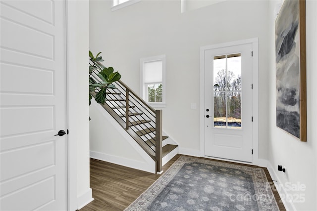 entryway with baseboards, wood finished floors, and stairway