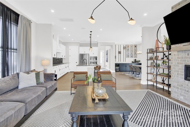 living area featuring light wood-style floors, a fireplace, recessed lighting, and visible vents