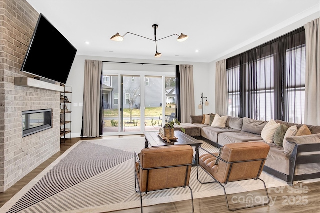 living area with a brick fireplace, recessed lighting, and wood finished floors