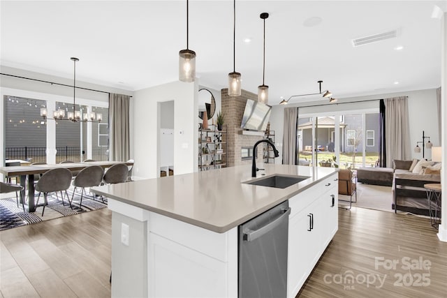 kitchen featuring stainless steel dishwasher, visible vents, open floor plan, a chandelier, and a sink