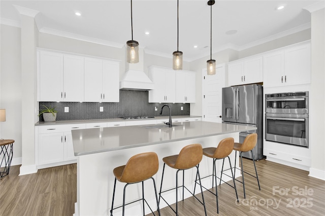 kitchen with light wood-type flooring, a sink, tasteful backsplash, and stainless steel appliances