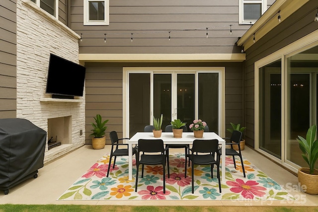 view of patio with an outdoor stone fireplace, outdoor dining area, and a grill