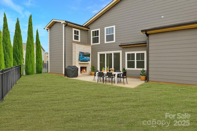 rear view of property featuring a yard, a patio, a lit fireplace, and a fenced backyard