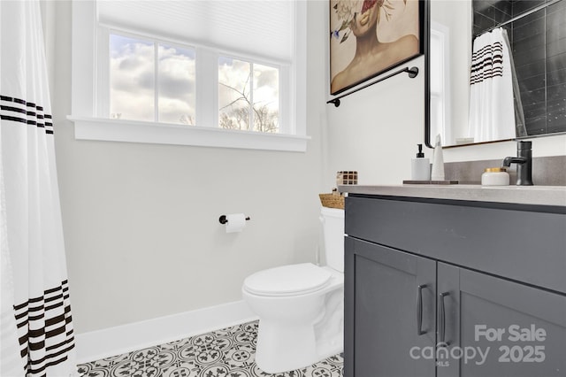 bathroom featuring toilet, baseboards, plenty of natural light, and vanity