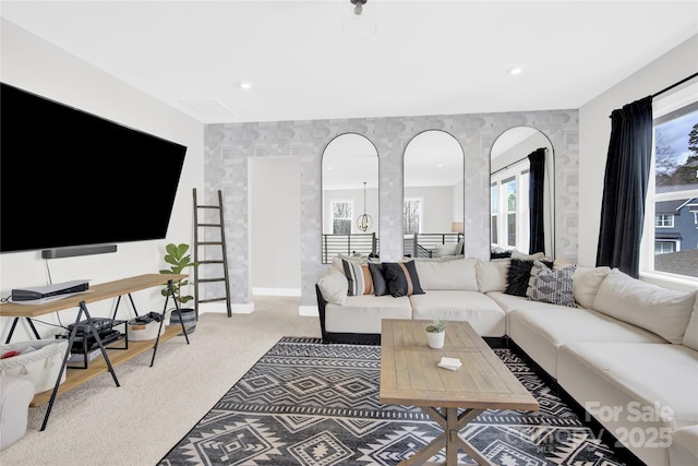 living area featuring arched walkways, baseboards, and light colored carpet
