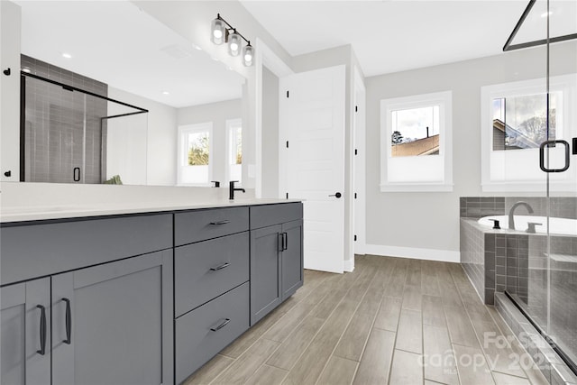 bathroom featuring double vanity, baseboards, a shower stall, a sink, and tiled bath
