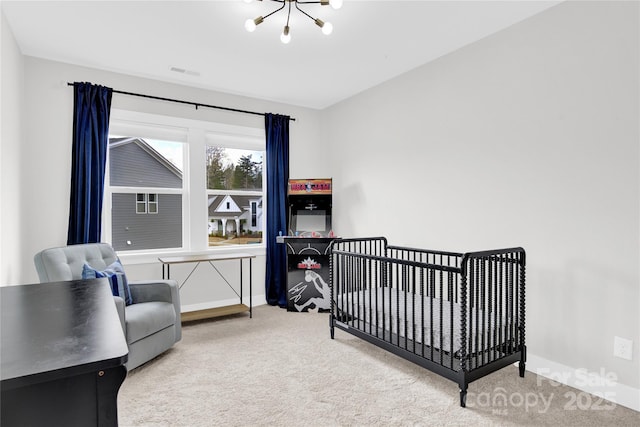 carpeted bedroom with a nursery area, baseboards, and a notable chandelier