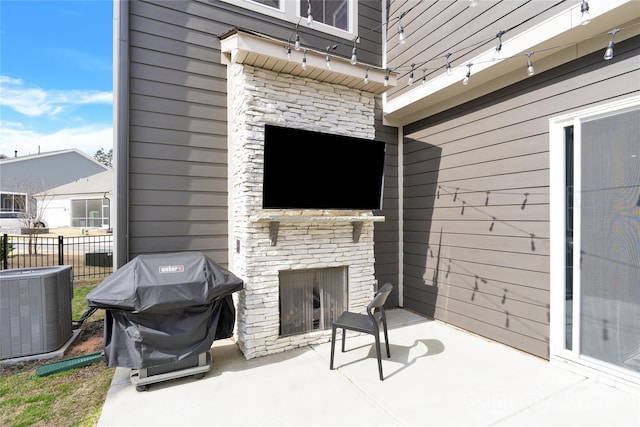 view of patio / terrace featuring fence, area for grilling, central AC, and an outdoor stone fireplace