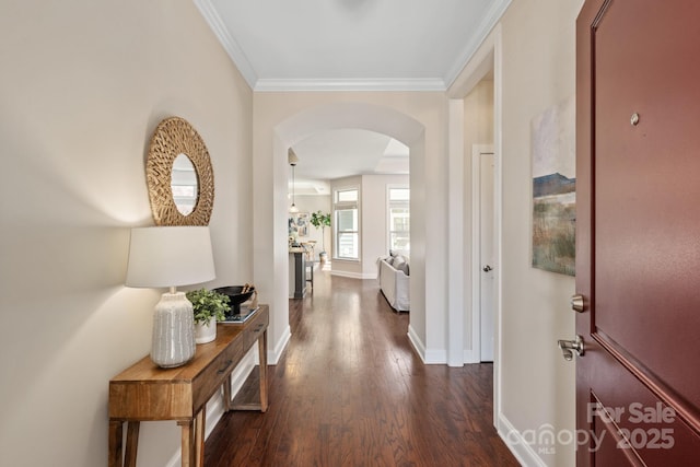hallway with baseboards, crown molding, arched walkways, and dark wood-style flooring