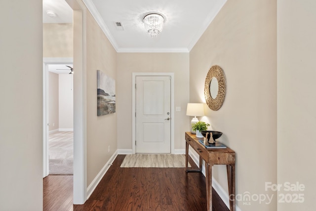 hall featuring baseboards, visible vents, crown molding, and dark wood-type flooring