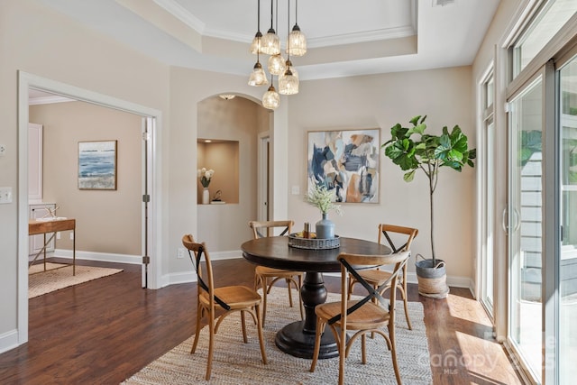 dining area with crown molding, baseboards, arched walkways, dark wood-type flooring, and a tray ceiling