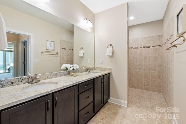 bathroom with double vanity, tile patterned flooring, a sink, and walk in shower