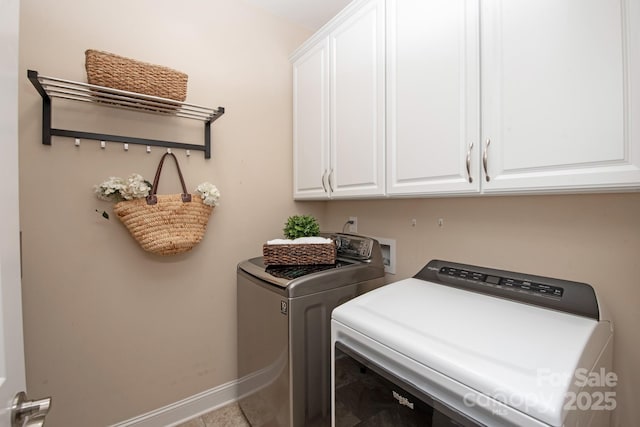 washroom with baseboards, cabinet space, and independent washer and dryer