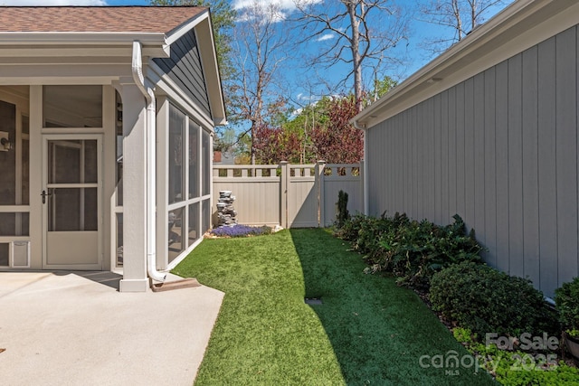 view of yard with a sunroom, a gate, fence, and a patio