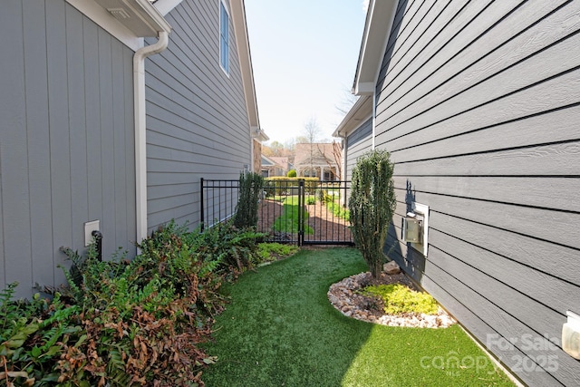 view of side of home with a lawn and fence