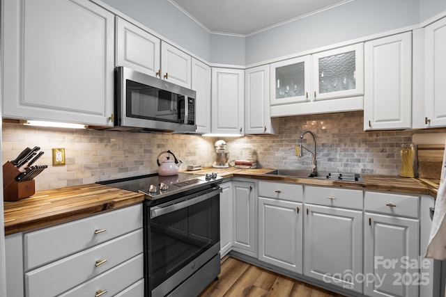 2503 Roswell Ave Unit 208, Charlotte, NC 28209 - kitchen featuring butcher block counters, stainless steel appliances, ornamental molding, white cabinets, and dark wood-style flooring