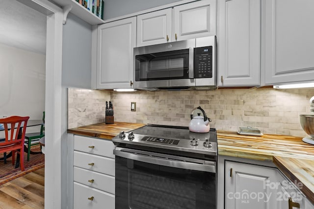 2503 Roswell Ave Unit 208, Charlotte, NC 28209 - kitchen featuring wood counters, stainless steel appliances, wood finished floors, decorative backsplash, and white cabinetry