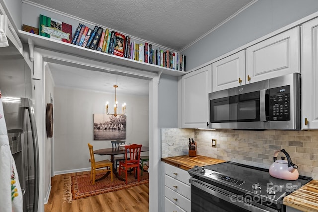 2503 Roswell Ave Unit 208, Charlotte, NC 28209 - kitchen featuring stainless steel appliances, ornamental molding, light wood-style floors, wood counters, and a chandelier