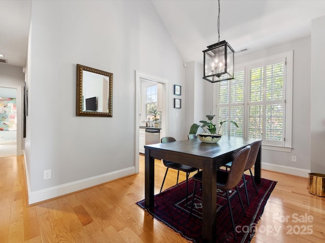 dining area with baseboards, a notable chandelier, visible vents, and light wood-type flooring