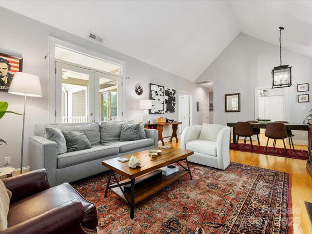 living room with visible vents, high vaulted ceiling, wood finished floors, and a chandelier