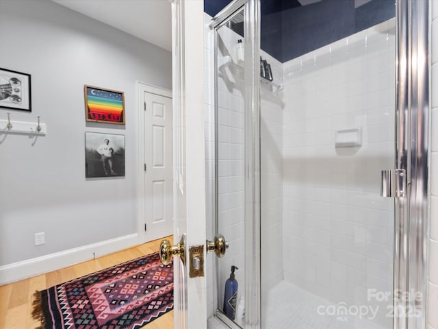 bathroom featuring baseboards, wood finished floors, and a stall shower