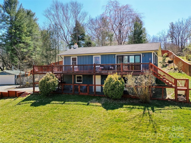 back of house featuring a chimney, board and batten siding, stairway, a wooden deck, and a lawn