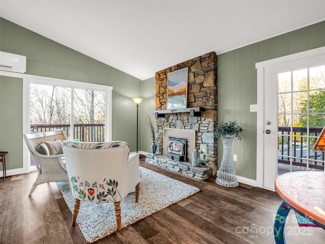 living room featuring a wall unit AC, baseboards, lofted ceiling, and wood finished floors
