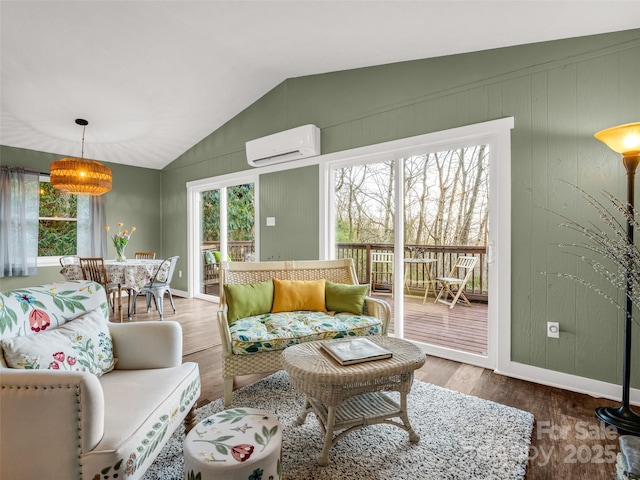 living room featuring baseboards, wood finished floors, vaulted ceiling, and an AC wall unit