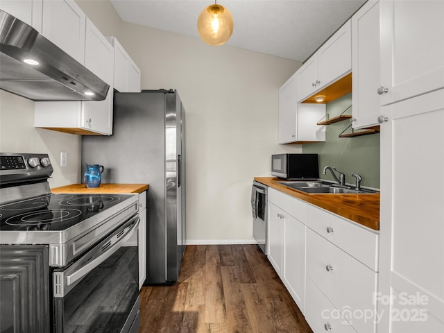 kitchen featuring extractor fan, a sink, butcher block counters, white cabinets, and appliances with stainless steel finishes