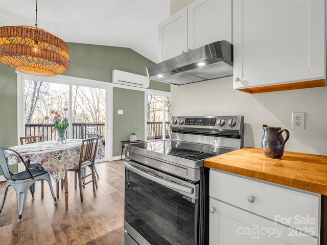 kitchen featuring vaulted ceiling, stainless steel range with electric cooktop, white cabinetry, under cabinet range hood, and an AC wall unit