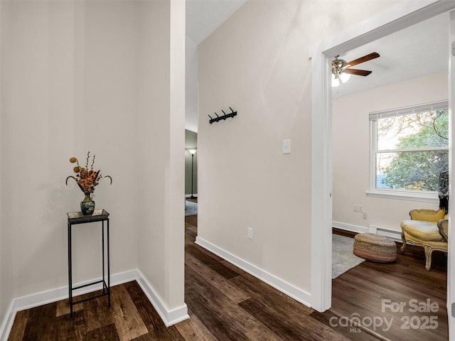 corridor with baseboards, a baseboard heating unit, and dark wood-style flooring