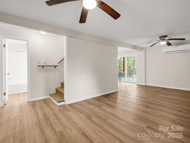 unfurnished living room with a wall mounted air conditioner, baseboards, stairway, a ceiling fan, and light wood-type flooring