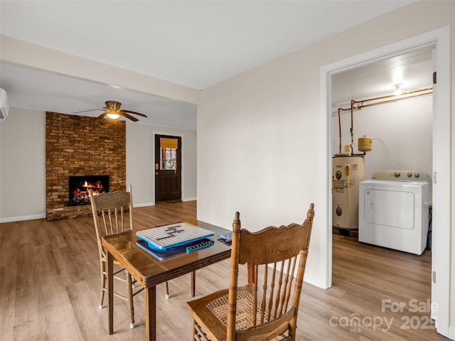 dining area with water heater, a ceiling fan, light wood finished floors, a brick fireplace, and washer / clothes dryer
