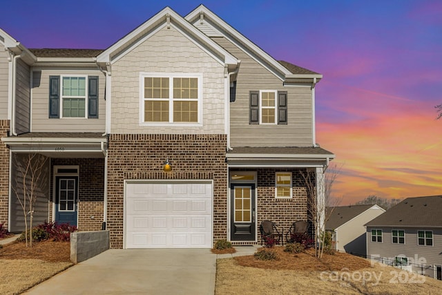 view of front of home featuring driveway, a garage, and brick siding
