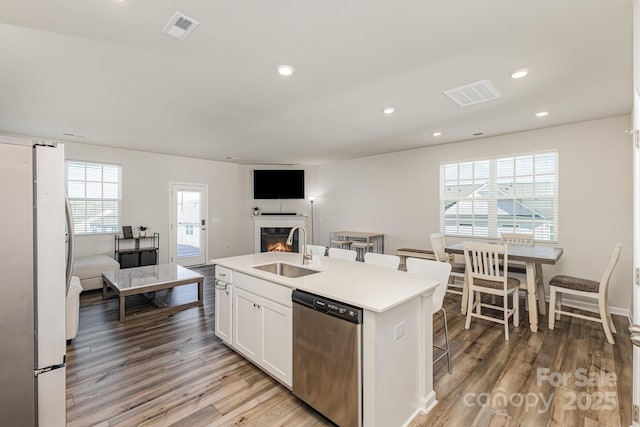 6048 Chelsea Oaks Rdg, Tega Cay, SC 29708 - kitchen with stainless steel appliances, a sink, light wood-style floors, open floor plan, and white cabinetry